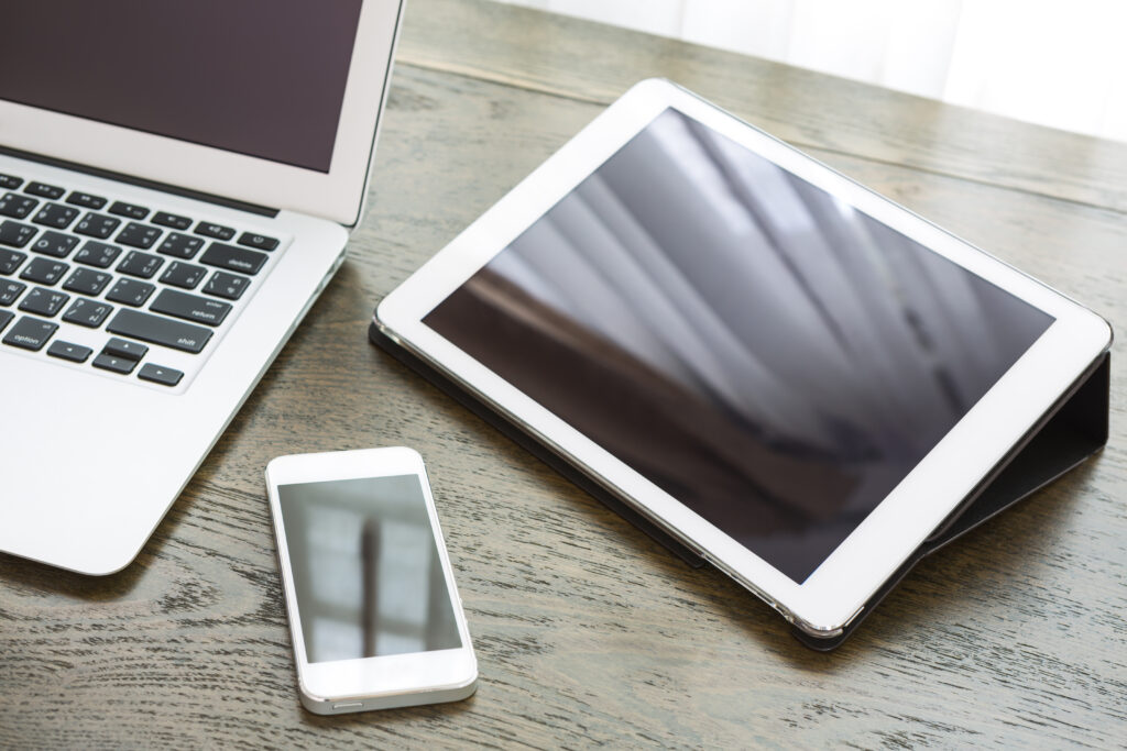An image of a latpop, mobile phone and tablet on a desk.